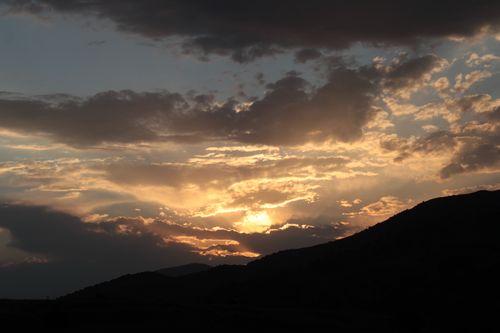 Free Captivating sunset with clouds over silhouetted mountains, showcasing nature's beauty. Stock Photo
