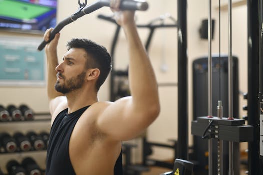 Man performing strength exercise on lat pulldown machine in gym.