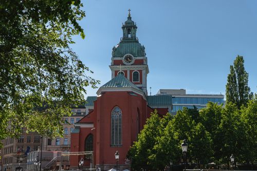 Free Beautiful view of St. James's Church with its distinct red facade and green roof against a clear blue sky in Stockholm. Stock Photo