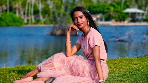 Free Elegant woman in pink tulle dress by serene lakefront on a sunny day. Stock Photo