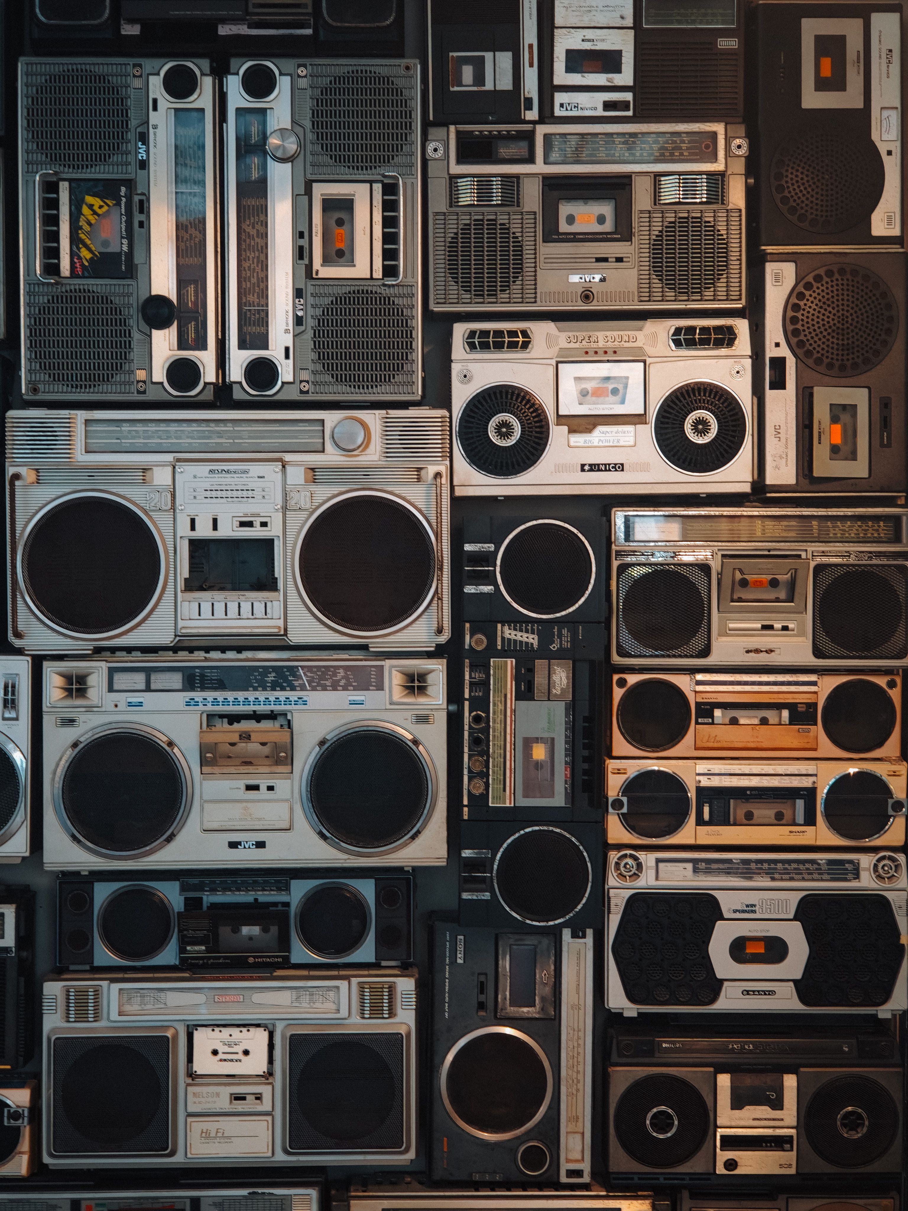 A collection of vintage boomboxes arranged on a wall, showcasing retro designs and technology.