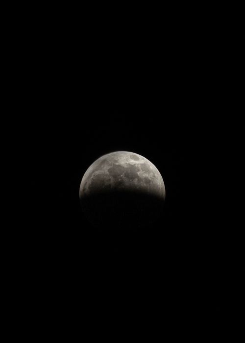 Free Capture of a partial lunar eclipse with a prominently shadowed moon in a dark sky. Stock Photo