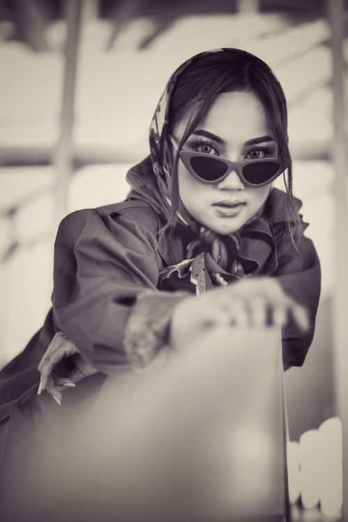 Free Black and white portrait of a fashionable woman wearing sunglasses and scarf indoors. Stock Photo