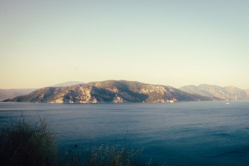 Free Tranquil coastal island landscape with calm blue waters under a clear sky at daytime. Stock Photo