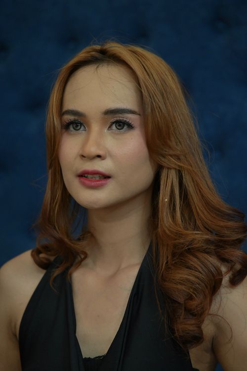 Free Close-up portrait of a woman against a deep blue background, displaying elegant, curly hairstyle. Stock Photo