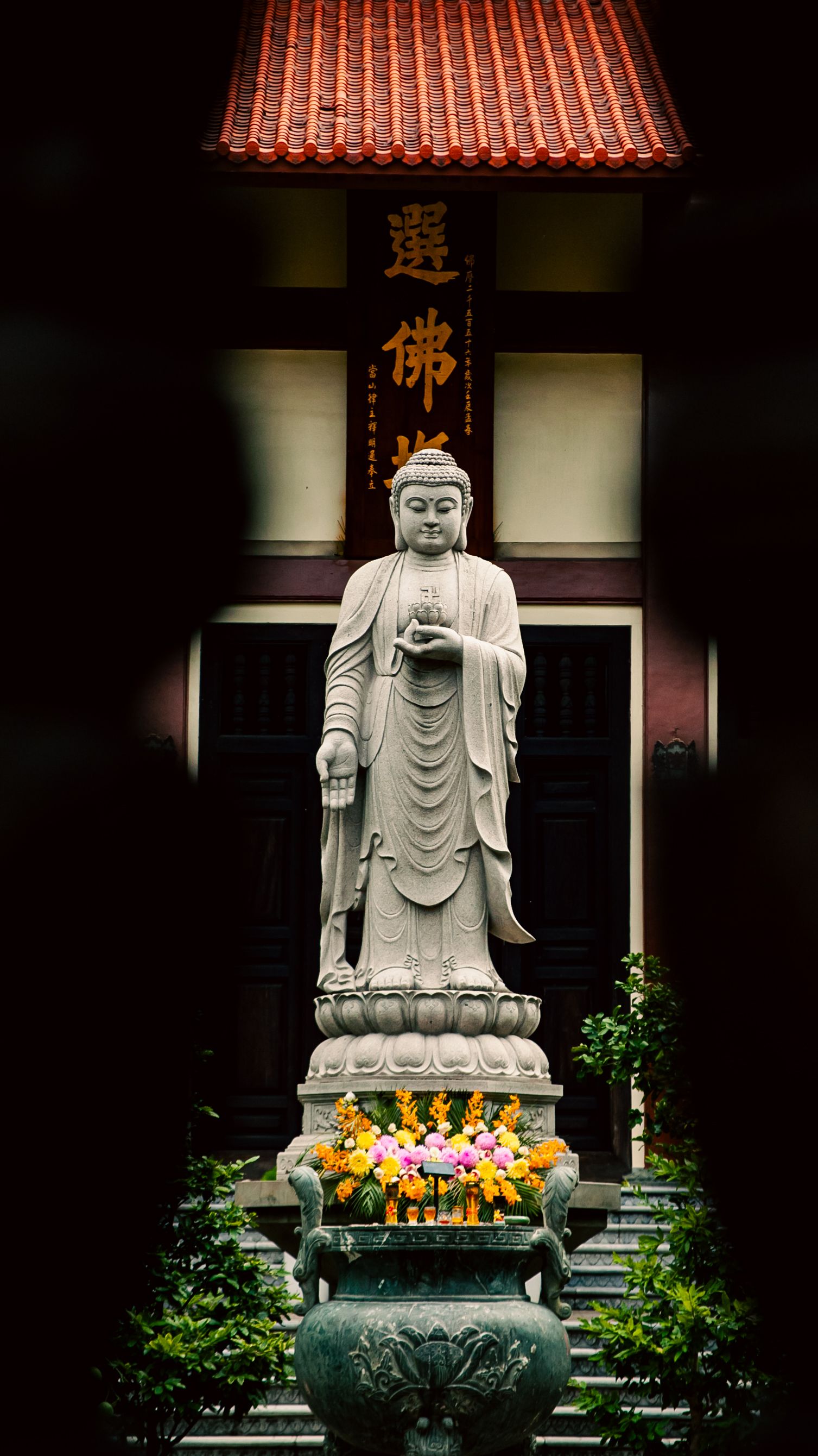 Serene stone Buddha statue outside a temple in Ho Chi Minh City, Vietnam, surrounded by greenery.