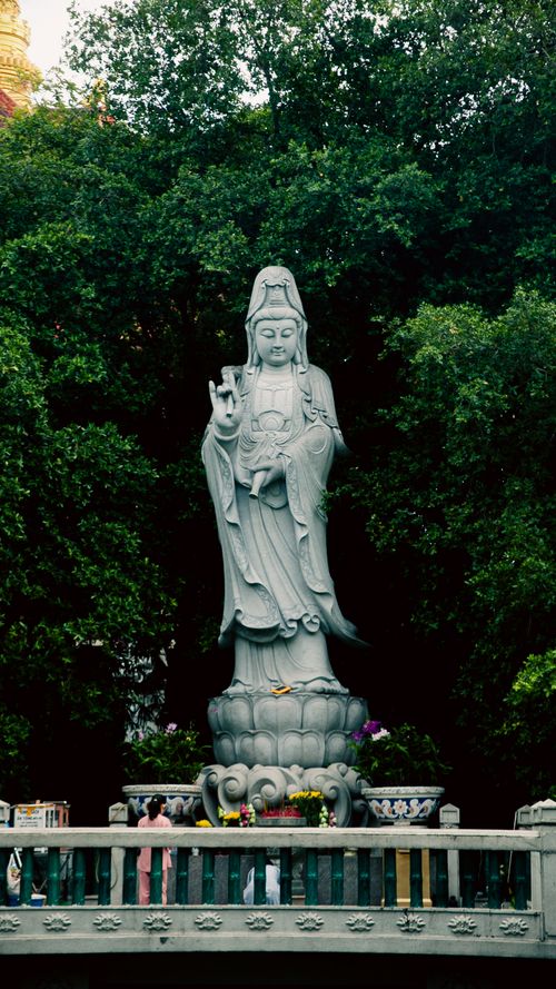 Free Guan Yin statue surrounded by lush greenery in Ho Chi Minh City, Vietnam, showcasing tranquil spirituality. Stock Photo