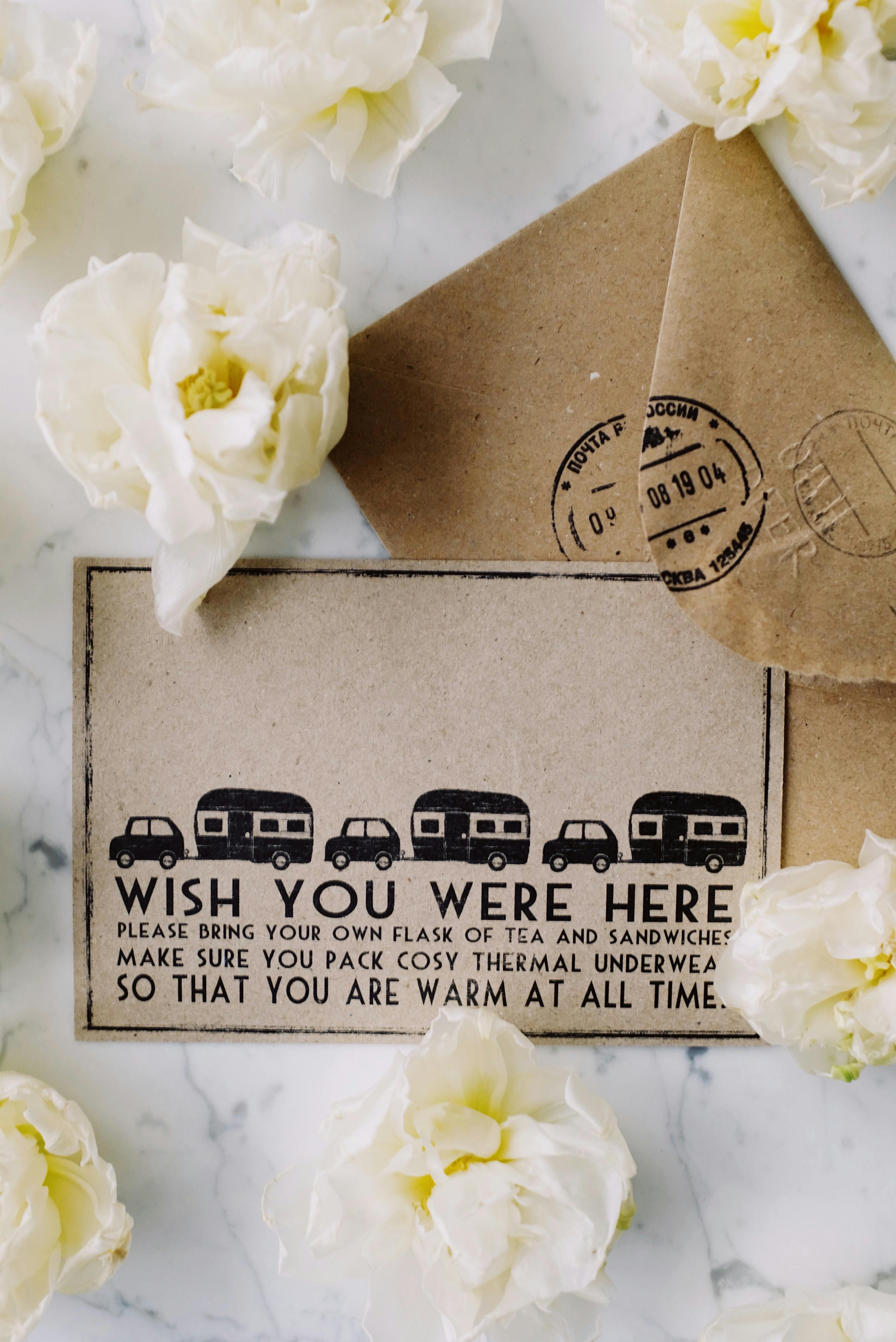 A vintage-style card with an envelope among white flowers on a marble surface.