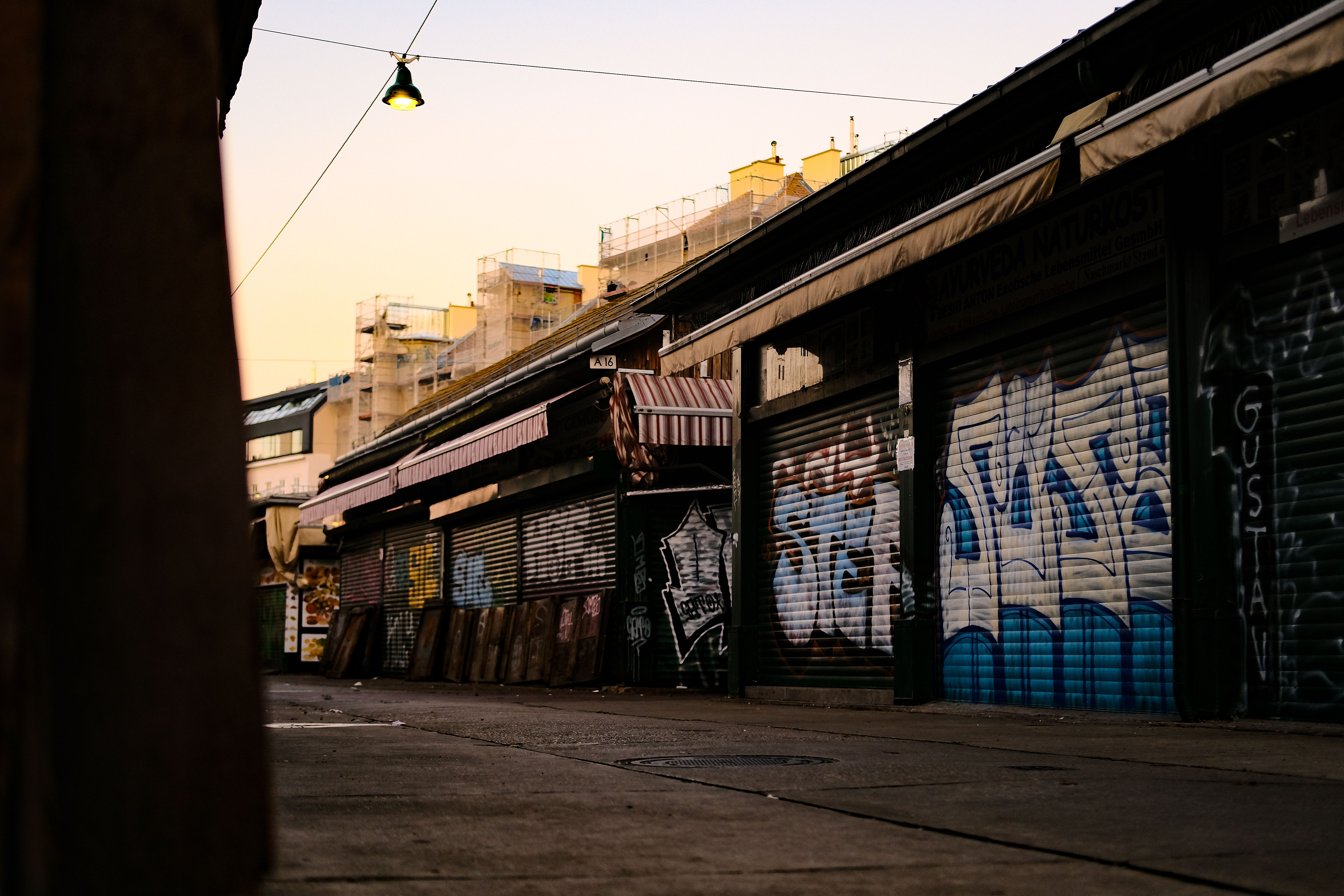 An empty Vienna street market with graffitied stalls at dawn, captured in a moody, street photography style.