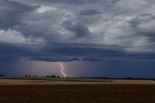 Free A stunning view of a lightning strike under stormy clouds across a rural landscape in France. Stock Photo