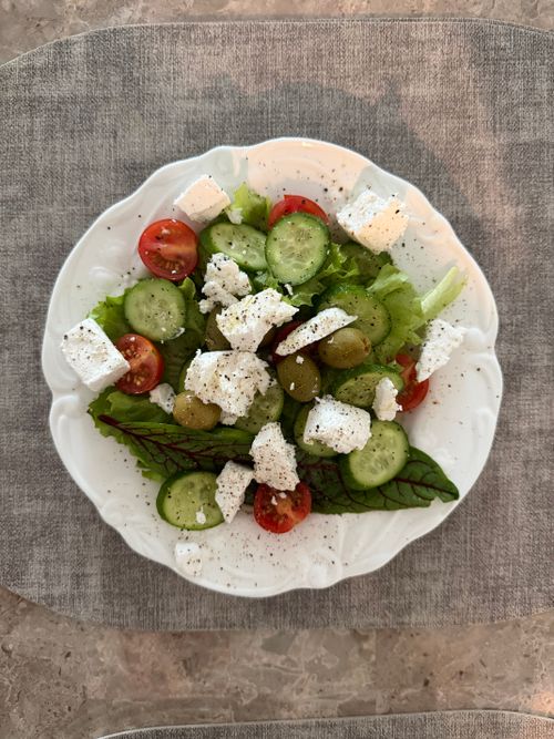 Free Delicious Greek salad with fresh vegetables, olives, and feta cheese on a white plate. Stock Photo