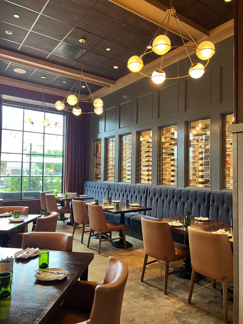 Free Stylish restaurant interior featuring cozy seating, modern lighting, and large windows with natural light. Stock Photo
