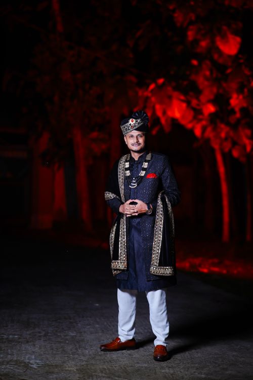 Free Elegant man in traditional royal attire with ornate details, standing outdoors at night. Stock Photo
