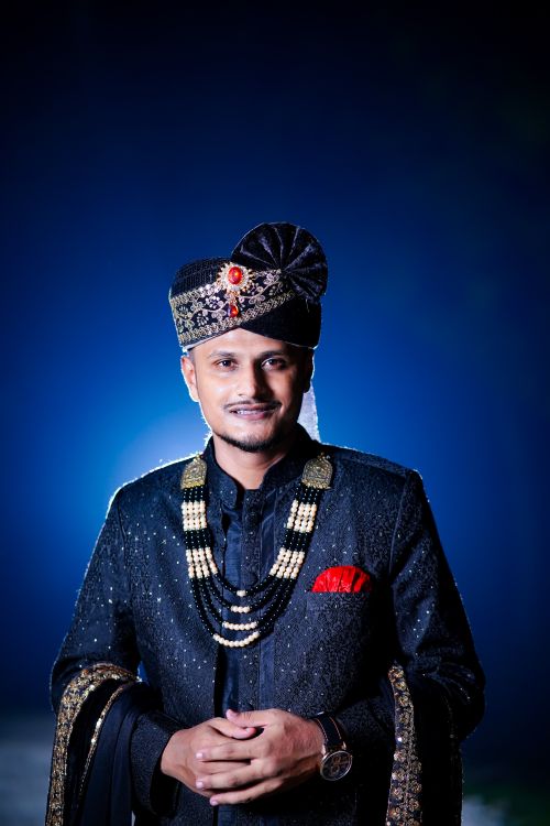 Free Portrait of an Indian groom wearing traditional attire with a dark blue background, captured at night. Stock Photo