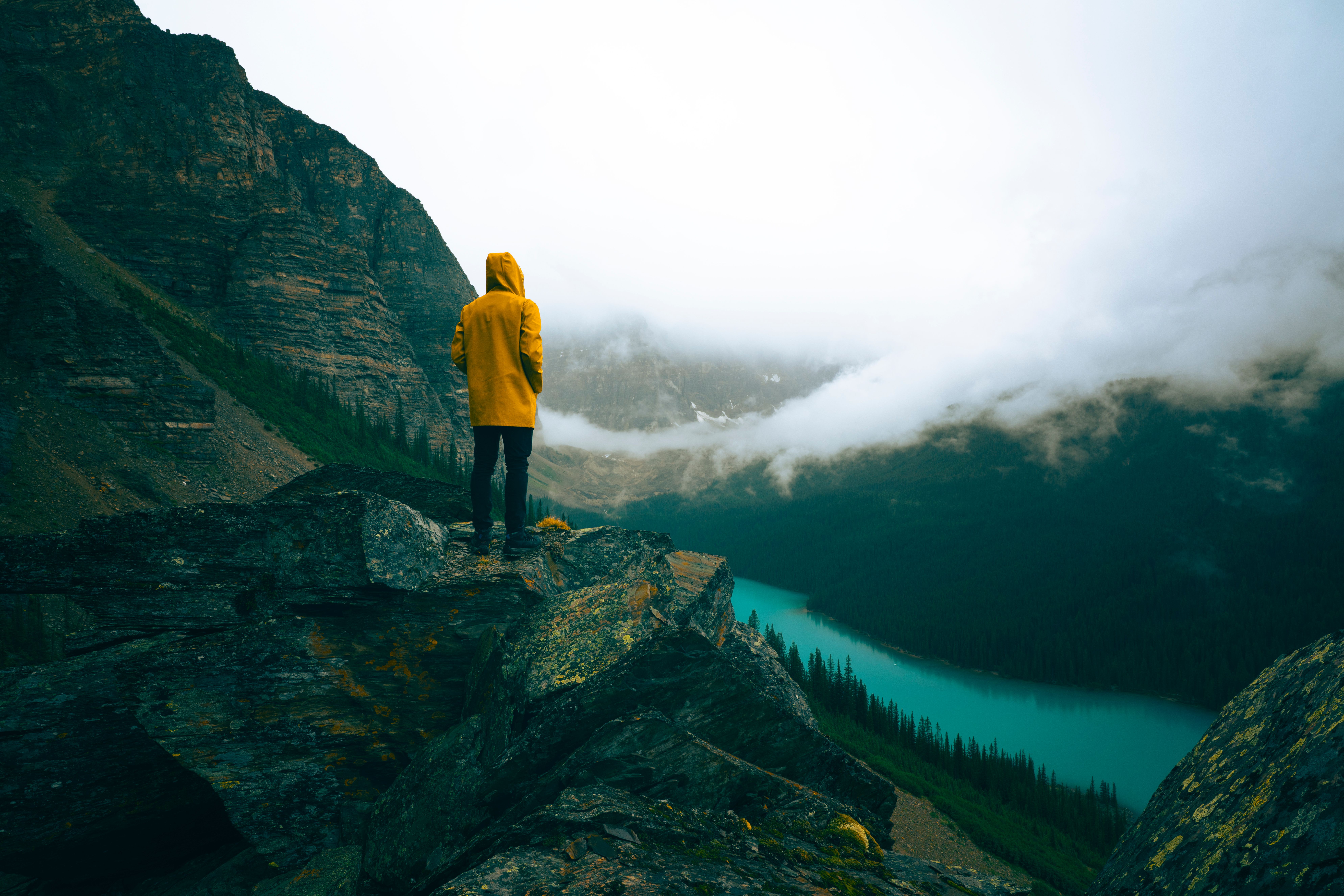 Person in yellow raincoat admires scenic view of Moraine Lake, Banff National Park.