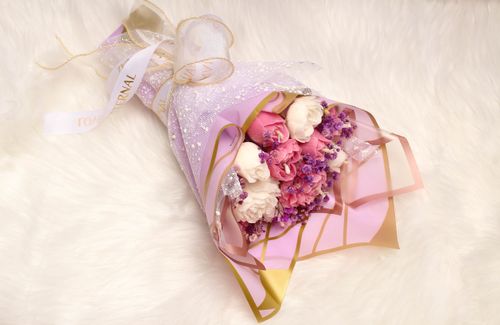 Free Stylish bouquet of pink and white flowers wrapped in elegant paper on a soft fur background, perfect for celebrations. Stock Photo