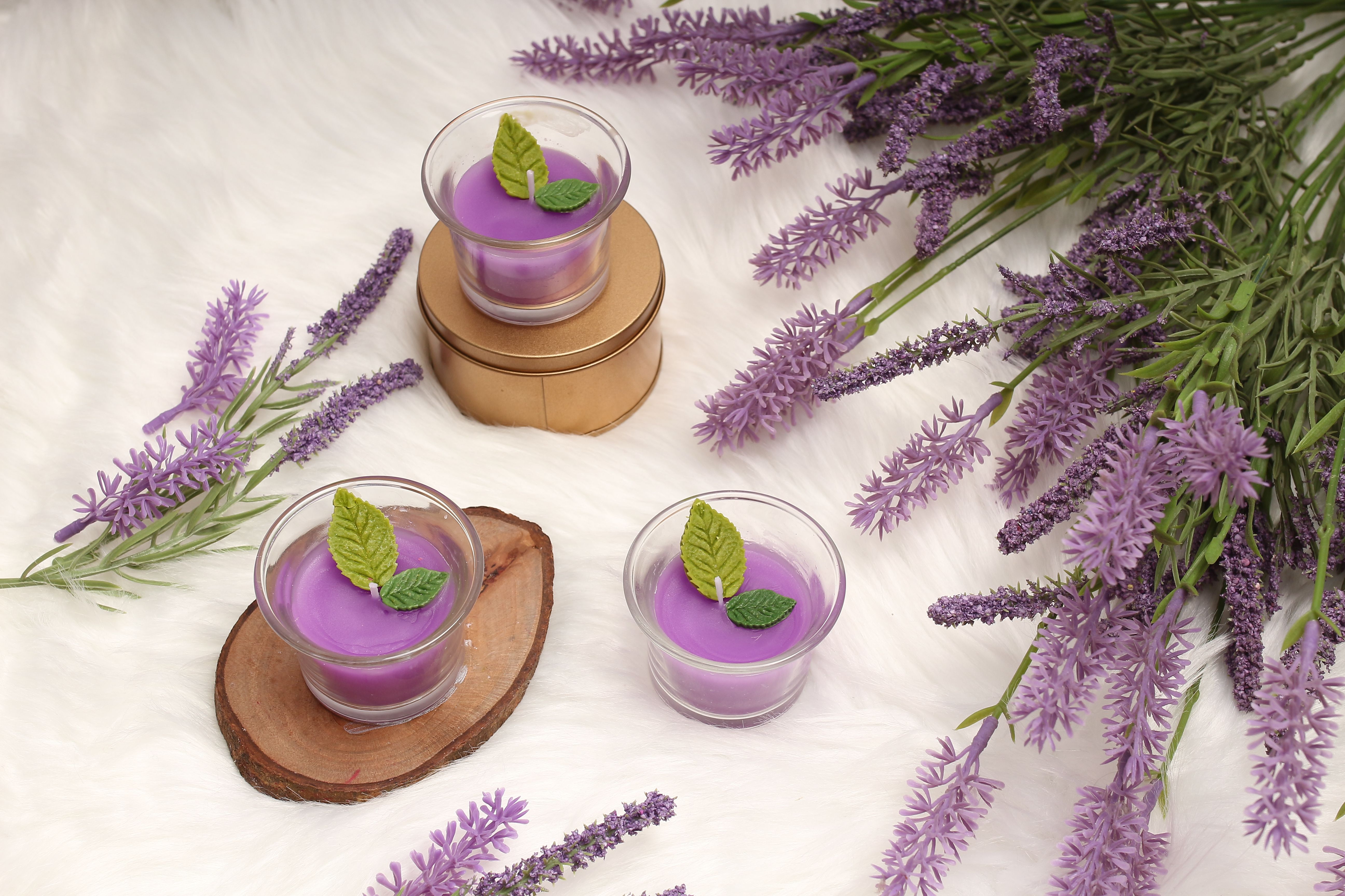 Lilac candles in small glasses among sprigs of lavender