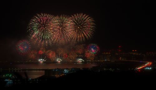Free Dazzling fireworks light up the night sky above a city skyline, reflecting on the water. Stock Photo