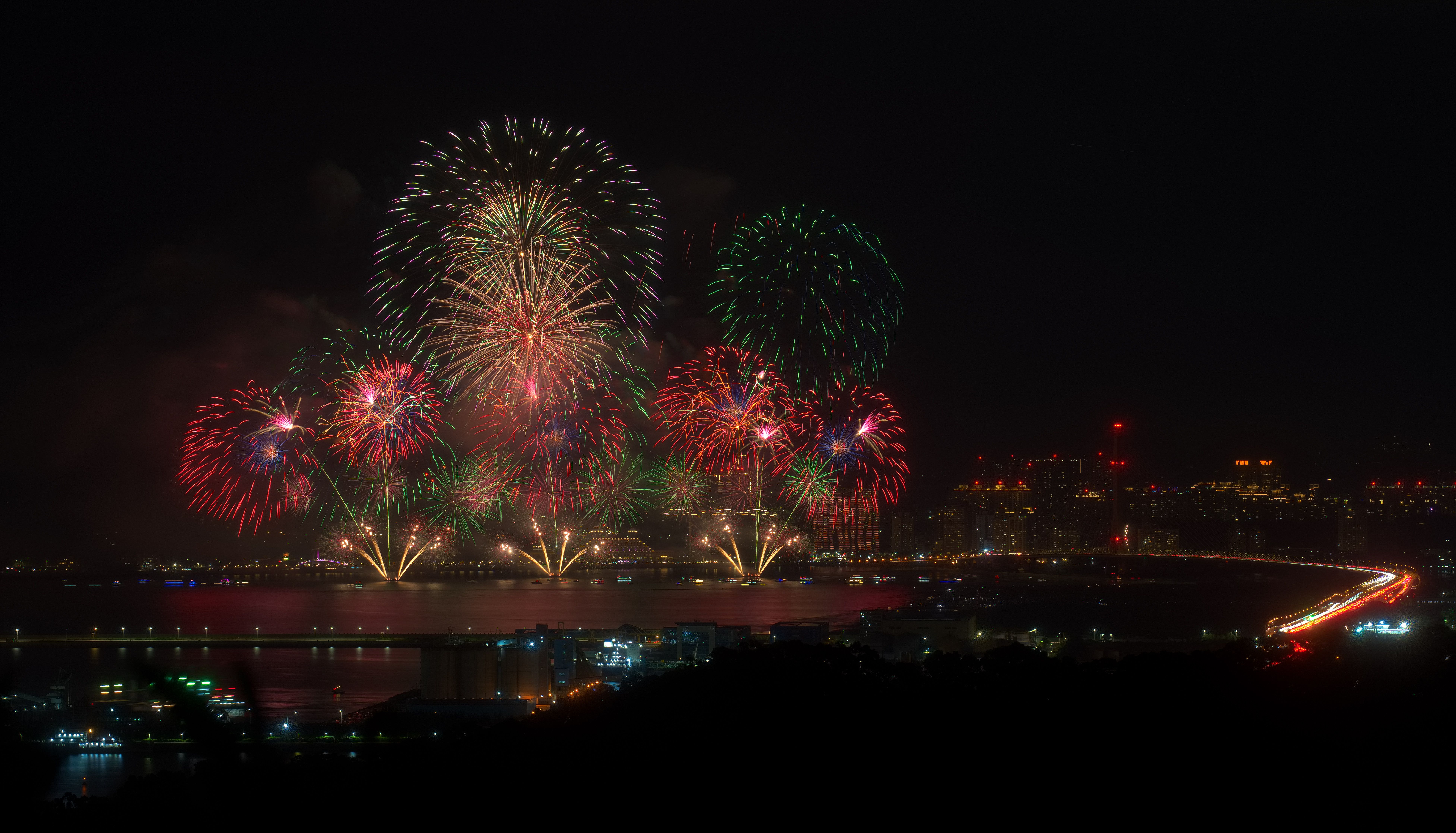 Fireworks over a city waterfront reflected in the water