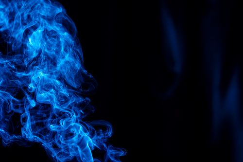 Free Dynamic blue smoke swirls create an abstract and ethereal design on a dark background. Stock Photo