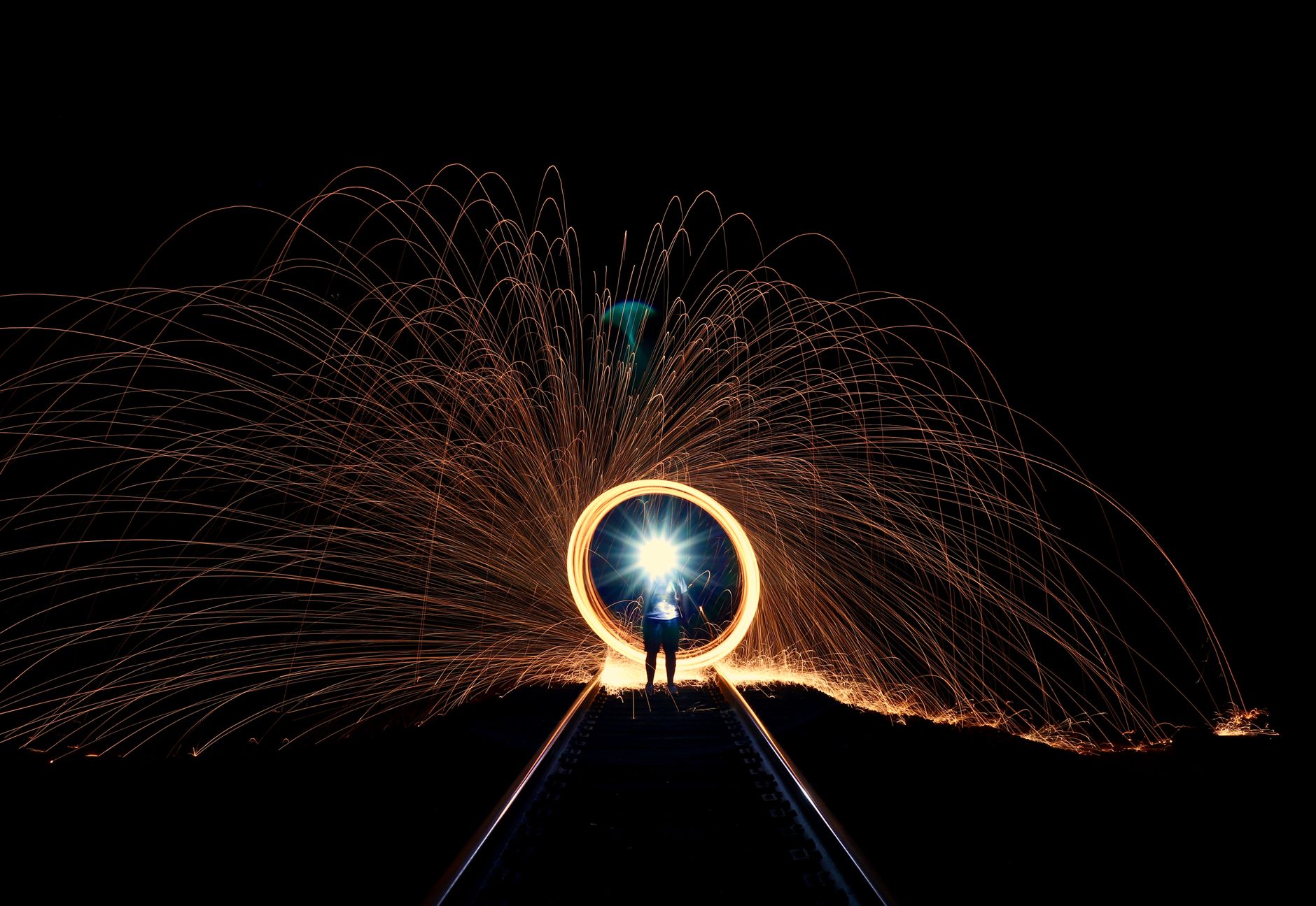 台中車軌光軌夜拍高點Top5:最佳位置與實戰技巧 A mesmerizing display of sparks and light along railroad tracks at night, showcasing artistic long exposure photography.