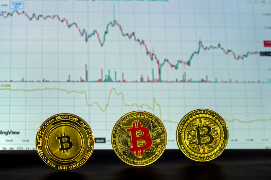 Tres monedas de Bitcoin frente a un gráfico financiero que muestra las tendencias y el análisis del mercado.