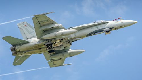 Free Royal Canadian Air Force CF-18 Hornet jet flying with visible vapor trails. Stock Photo