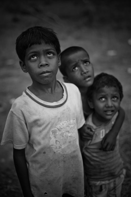 Free A compelling black and white portrait of three children gazing upwards, outdoors. Stock Photo