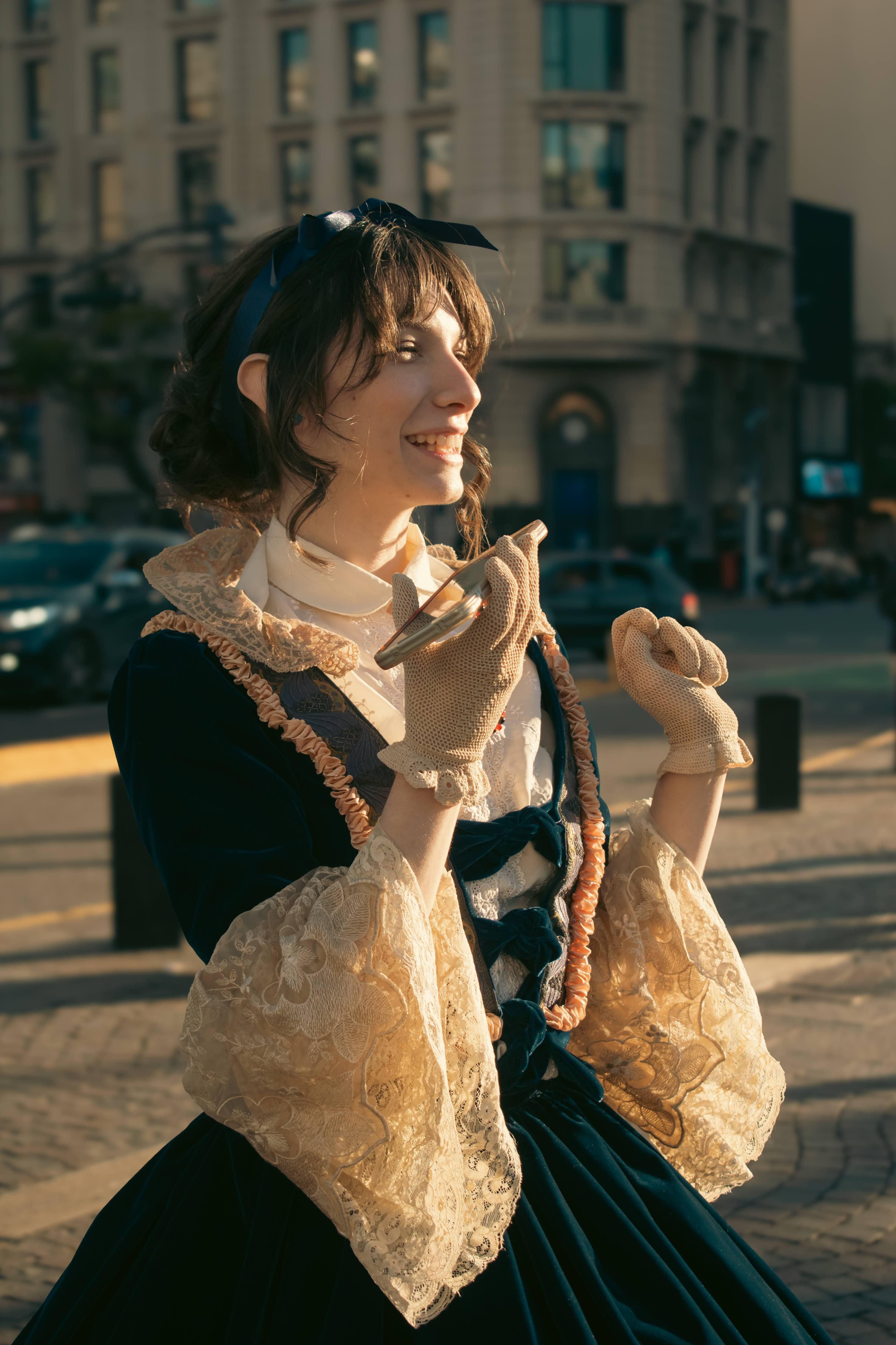 A woman in period costume smiling on a sunny street in Buenos Aires.