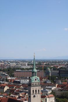 Aerial view of Munich with a historic church tower and cityscape on a sunny day.