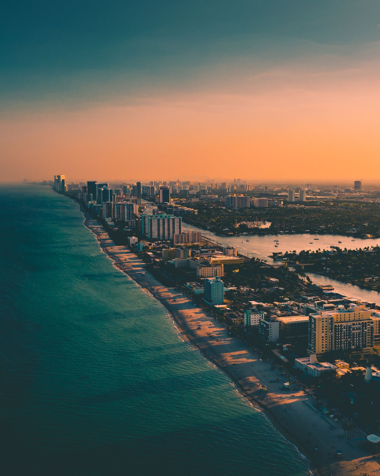 Aerial shot of city buildings meeting the ocean at sunset