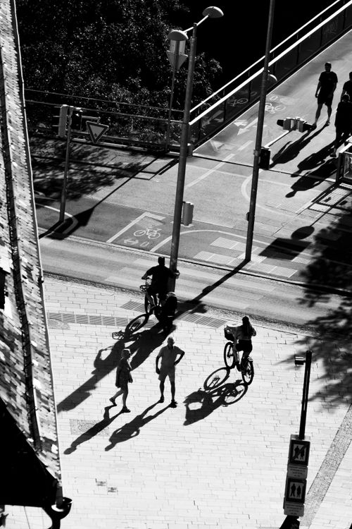 Free High-angle view of cyclists and pedestrians casting shadows on a city street. Stock Photo
