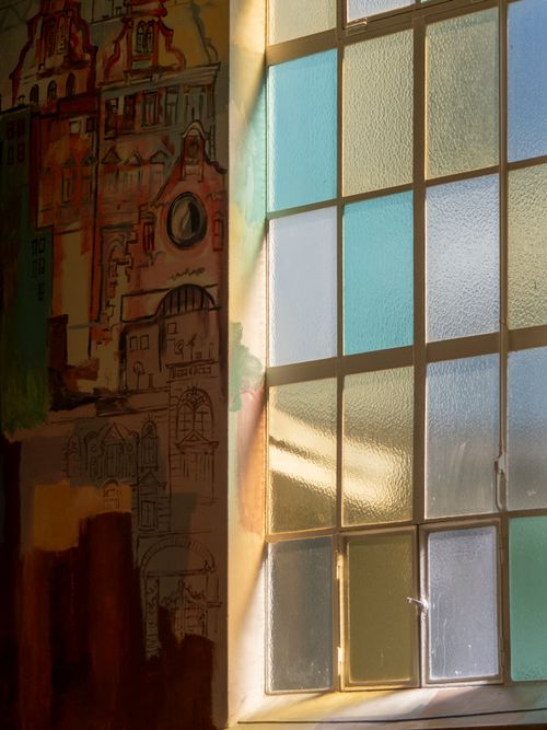 Free Warm sunlight through a stained glass window illuminates an artistically painted wall. Stock Photo