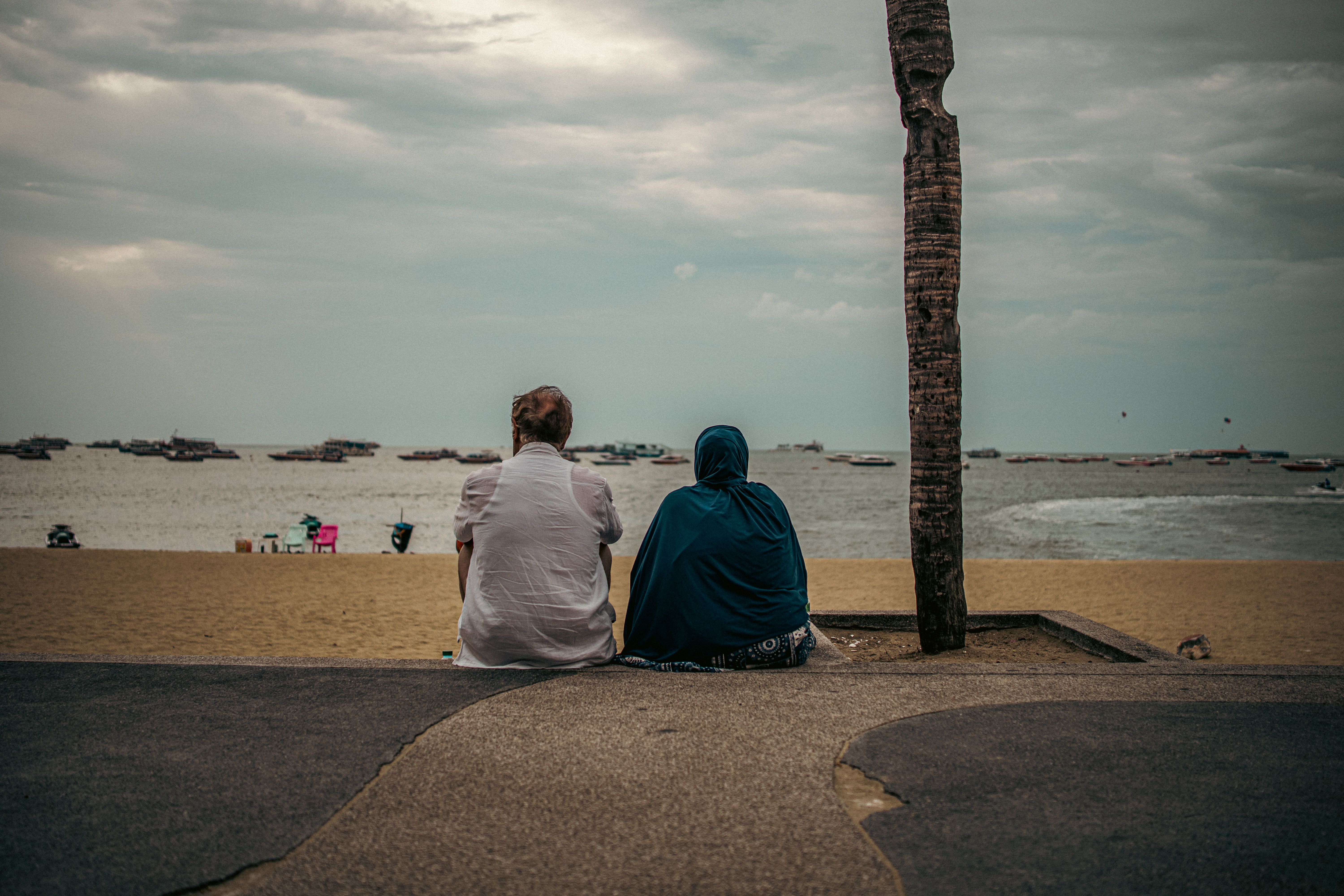 Two people sitting on a quiet beach on the Thai coast.