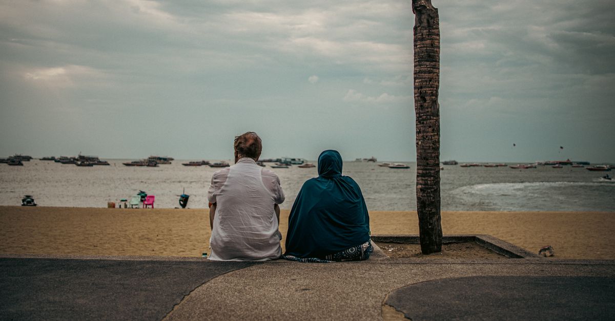 Two people sitting on a quiet beach on the Thai coast.