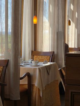 Intimate restaurant table setting with warm curtains and soft lighting, creating a cozy dining atmosphere.