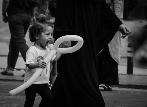 Free Black and white photo of a child holding a balloon on a street in Bursa, Türkiye. Stock Photo
