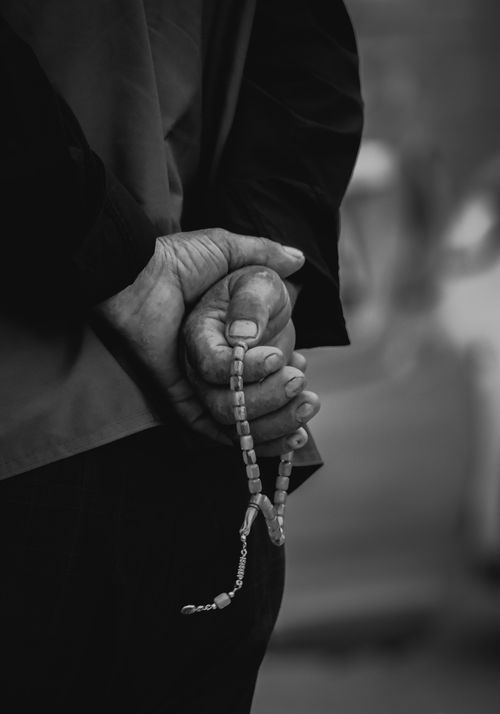 Free Black and white photo of hands holding prayer beads, signifying reflection. Stock Photo