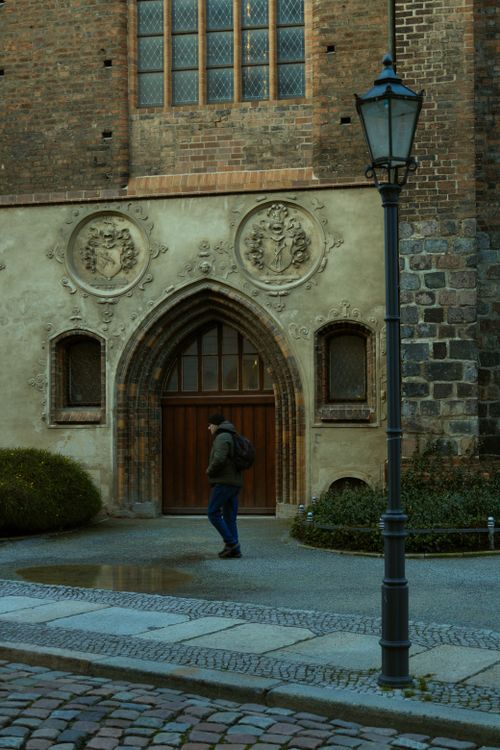 Free A person walking by a Gothic-style church facade in Berlin, Germany, during the early morning. Stock Photo