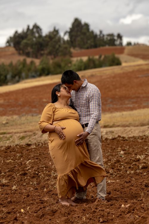 Free Pregnant woman and partner share a tender moment in a picturesque countryside field. Stock Photo