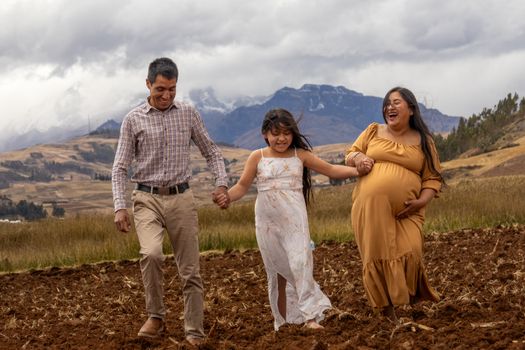 A joyful family walking hand in hand through a mountainous field, capturing a moment of togetherness.