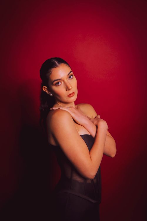Free Modern portrait of a woman posing elegantly against a vivid red backdrop. Perfect for lifestyle and fashion themes. Stock Photo