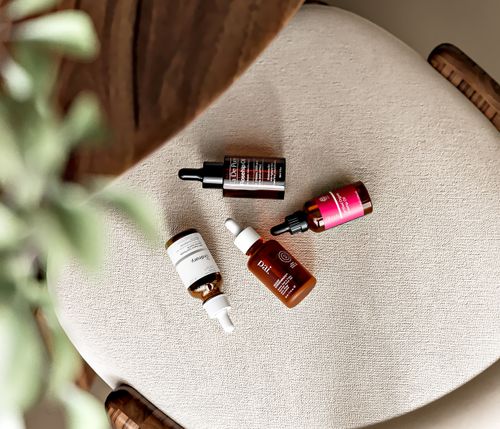 Free Top view of various natural skincare serums arranged on a chair, highlighting clean beauty and skin nourishment. Stock Photo