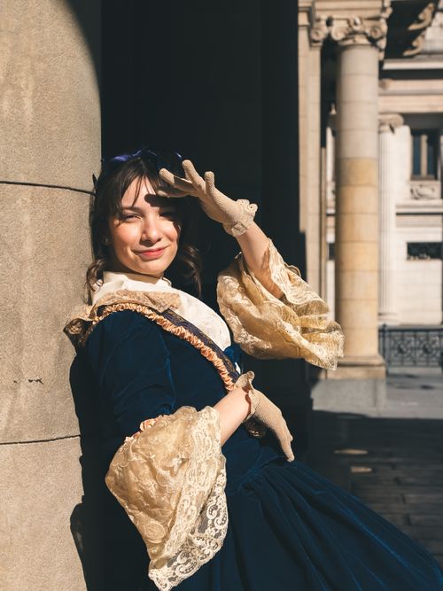 Free A woman in a vintage dress poses under sunlight at Teatro Colon, Buenos Aires. Stock Photo