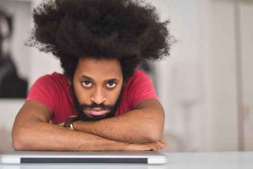 Free Captivating portrait of a man with a voluminous afro hairstyle leaning forward with a thoughtful expression. Stock Photo