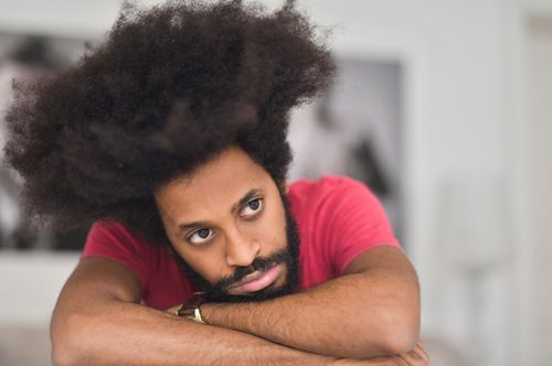 Free Thoughtful portrait of man with afro hairstyle in natural light, wearing a red shirt. Stock Photo
