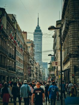 Crowds fill the bustling Madero Street beneath the iconic Torre Latinoamericana in Mexico City.