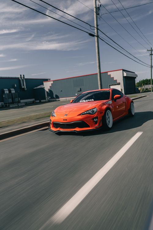 Free Dynamic shot of an orange sports car speeding down a city street on a clear day. Stock Photo