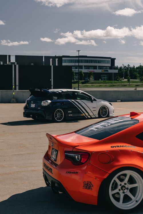 Free Two modified cars on rooftop parking, sports car enthusiasts showcase. Stock Photo