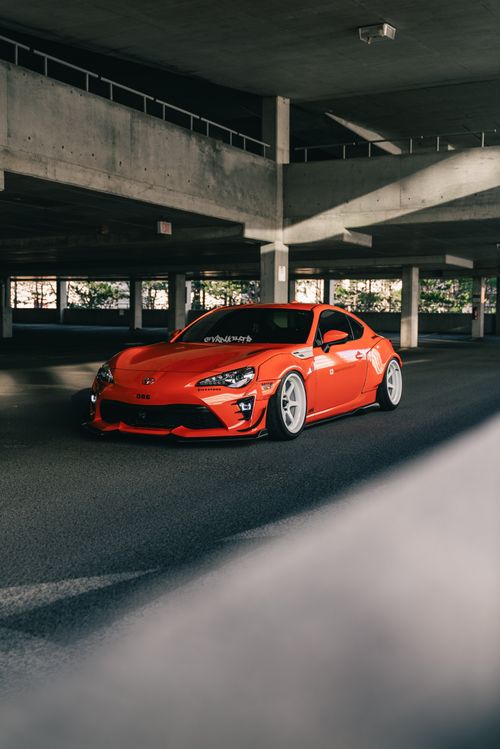 Free A bright red sports car parked in an empty parking garage under soft natural light. Stock Photo